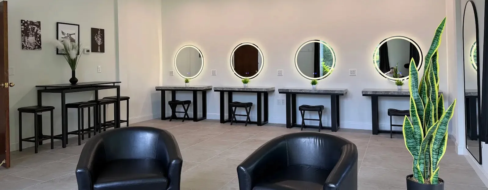 vanity mirrors against a white wall with chairs around them in a dressing room