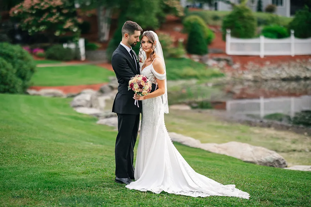 Austin looks are Erica while Erica looks at the camera, both in their wedding attire next to a lake